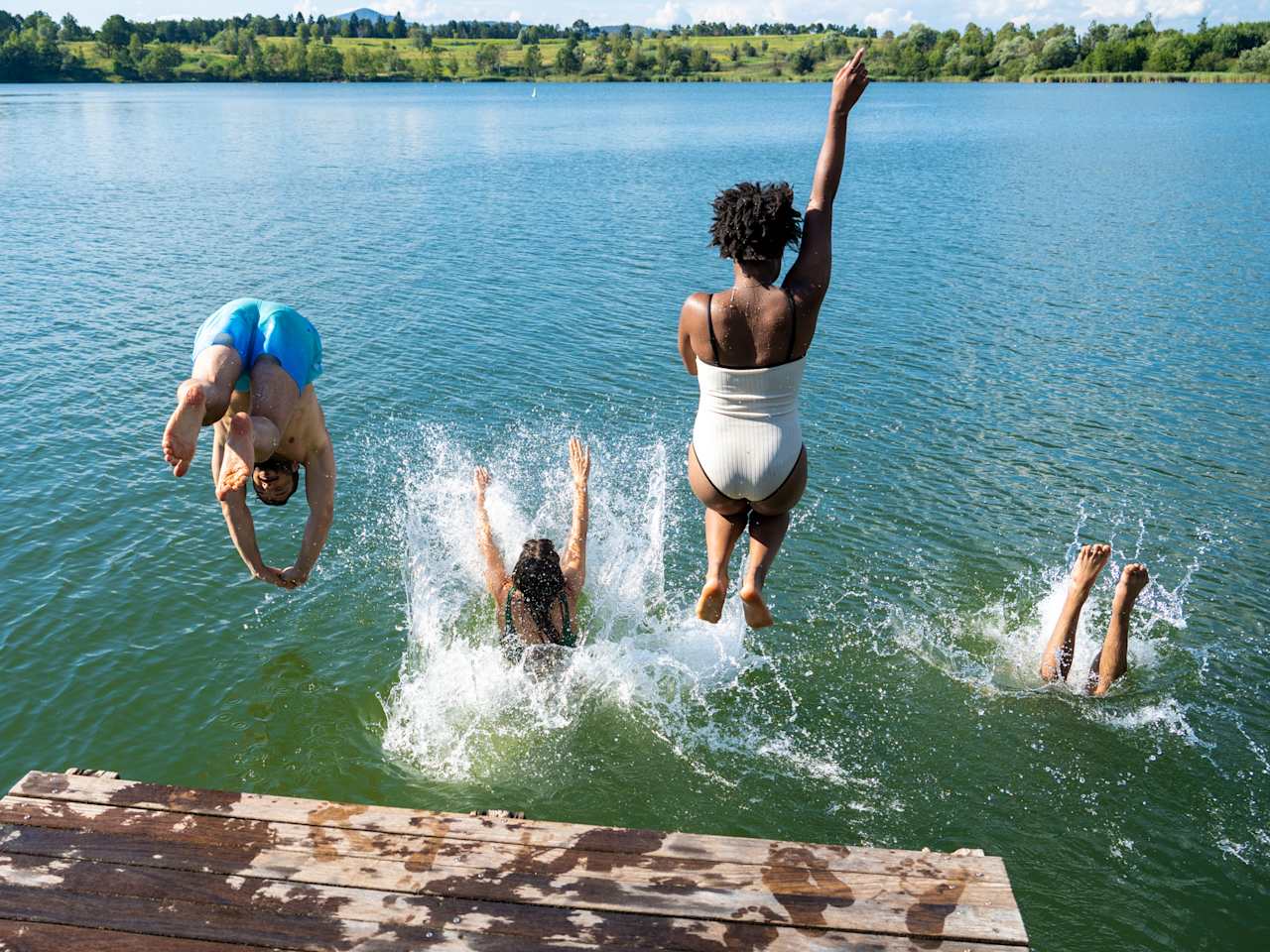 Mehrere Personen springen in das Wasser eines Sees