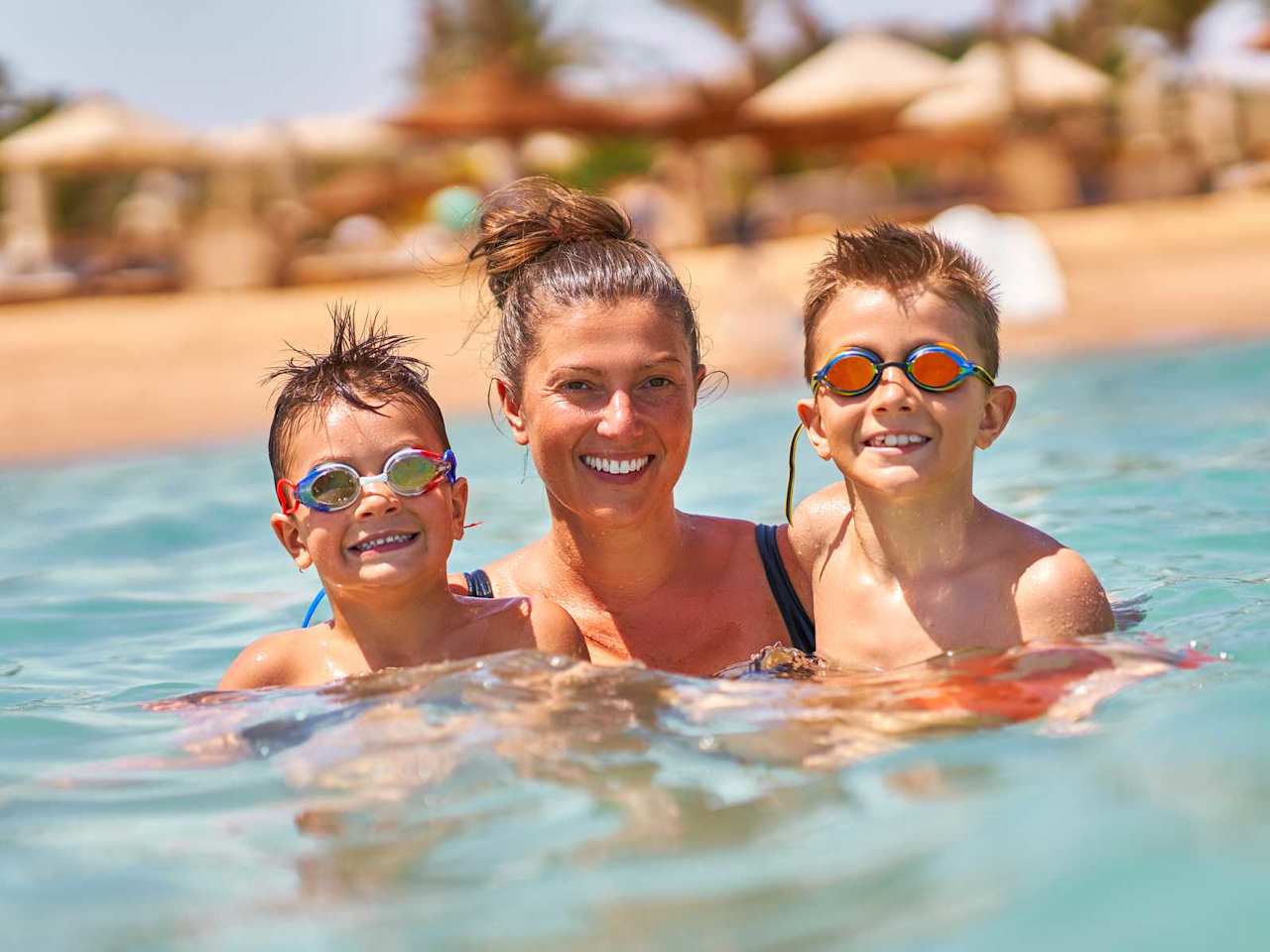 Eine Mutter schwimmt mit ihren beiden Söhnen im Meer und haben Spaß.