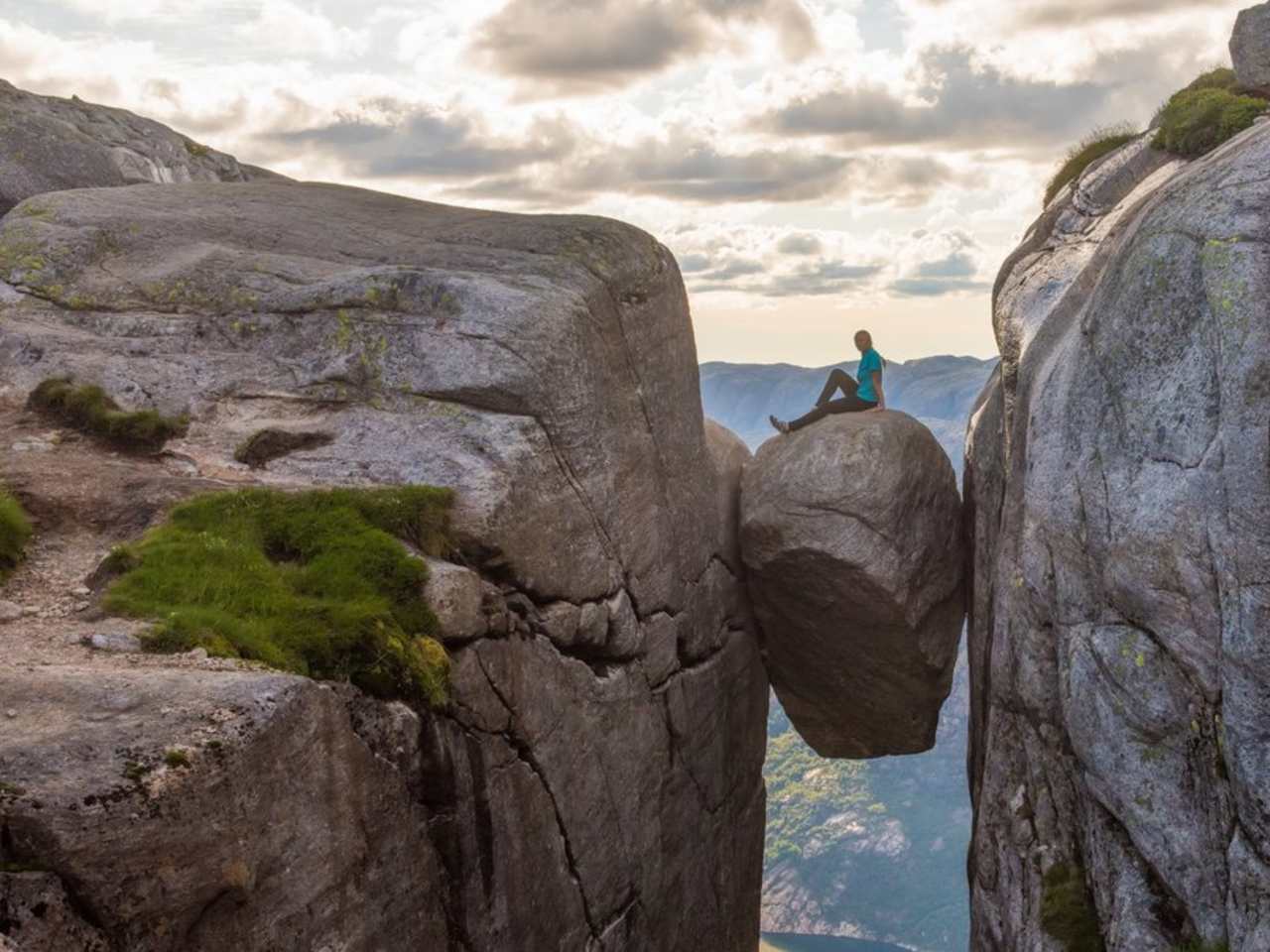 Eine Touristin auf dem norwegischen Kjeragbolten. © iStock via Getty/kotangens