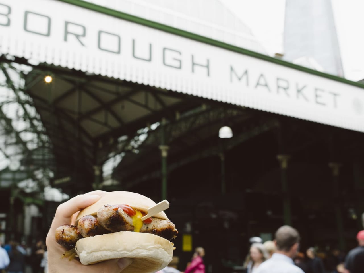 Ein Mann hält ein Sandwich vor dem Borough Market in London.
