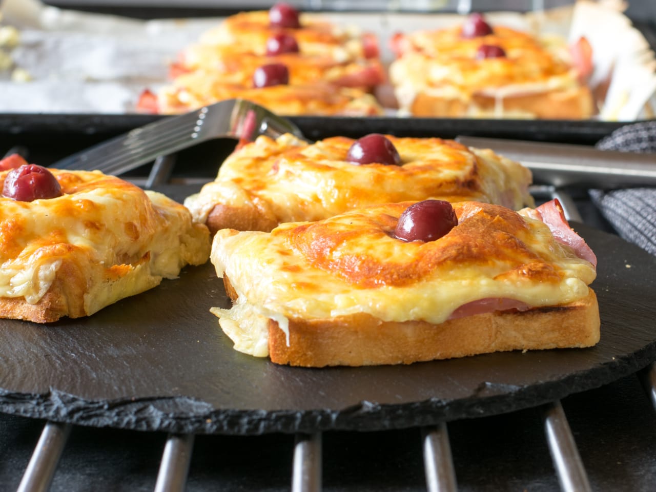 Überbackender Toast Hawaii mit Schinken, Käse und einer Kirsche.