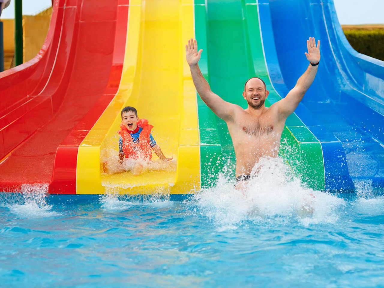 Vater und Sohn haben Spaß auf einer Wasserrutsche.