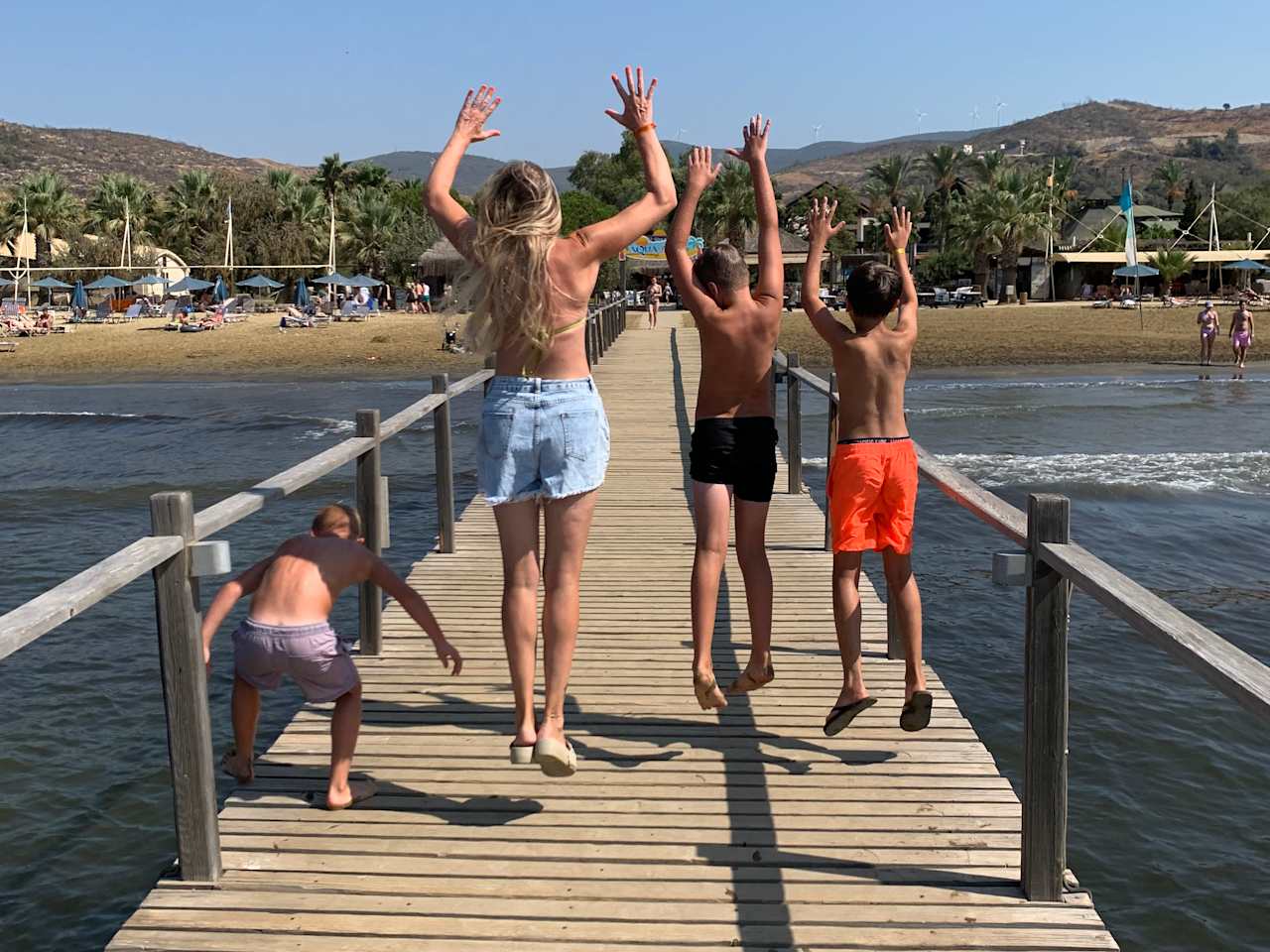 Frau mit drei Jungs auf einen Steg im Meer.