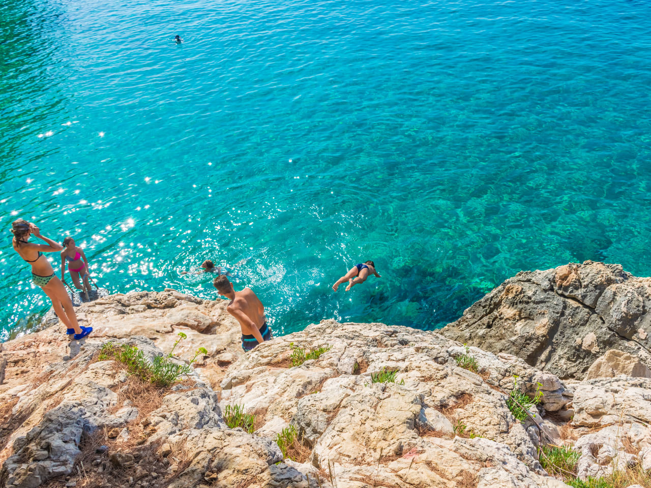 Kinder springen ins Meer von Klippen am Jagodna Beach auf der Insel Hvar, Kroatien