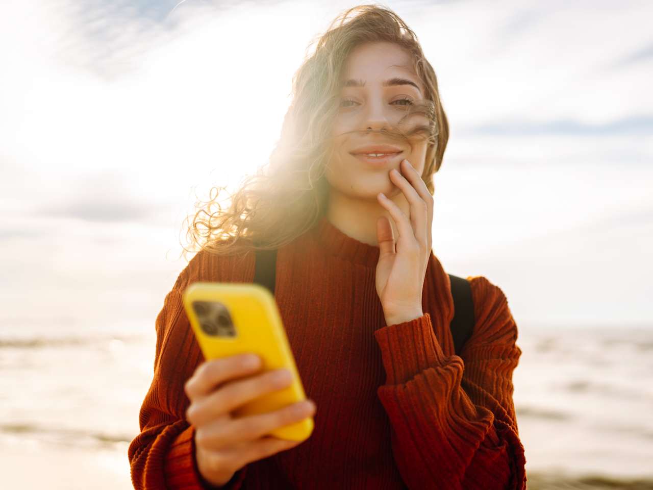 Frau mit Smartphone am Strand.