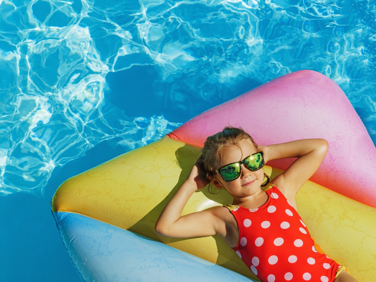 Kind liegt auf Luftmatratze im Pool.