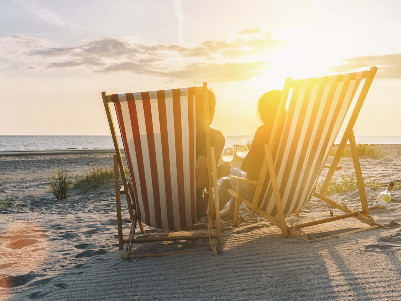Zwei Personen in Liegestühlen im Sonnenuntergang am Ostseestrand