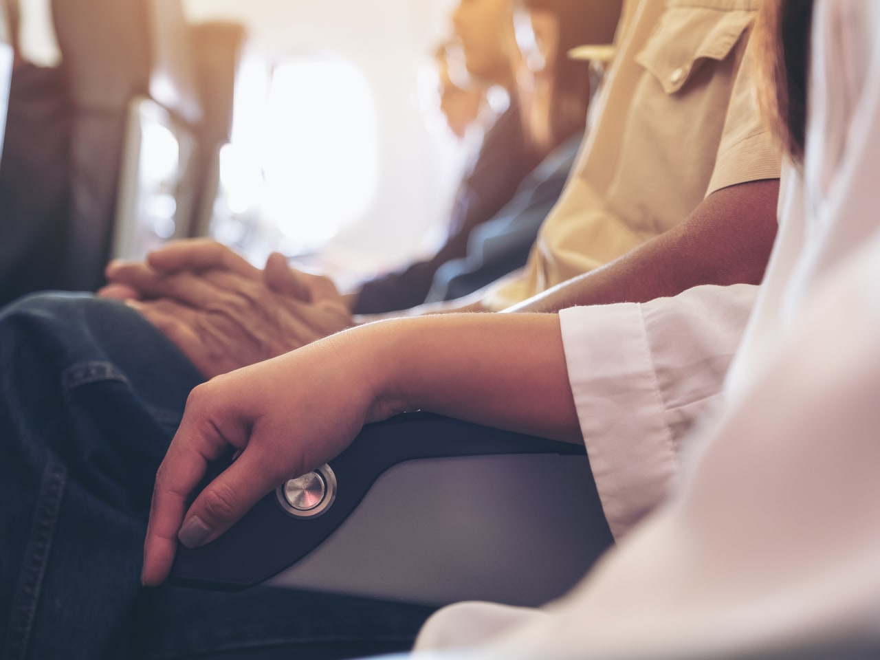 Frau und Mann teilen sich Armlehne im Flugzeug.