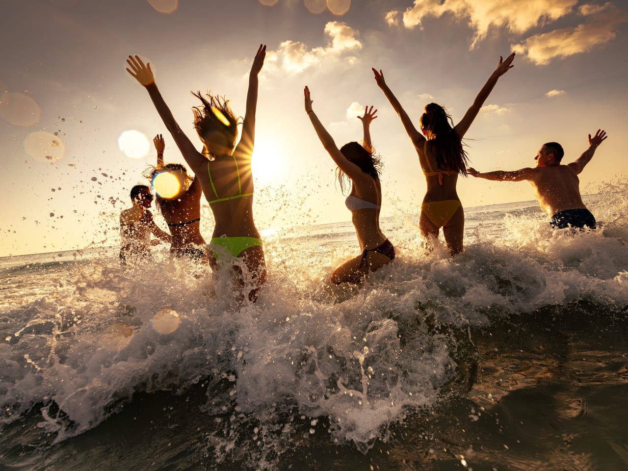 Eine Gruppe Frauen und Männer feiert eine Party am Strand im Meer.