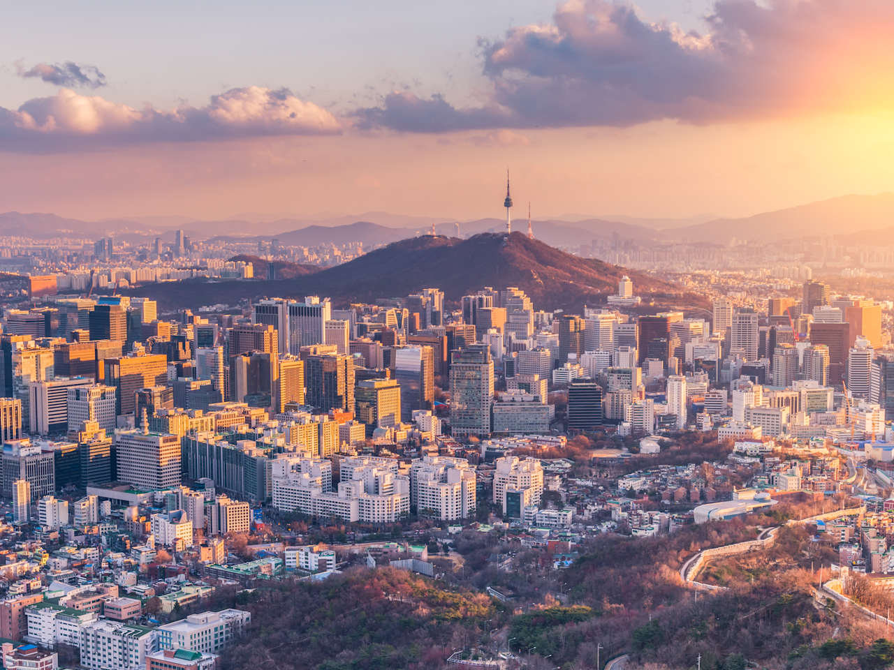 Ein Sonnenuntergang über einer Großstadt mit Bergen im Hintergrund