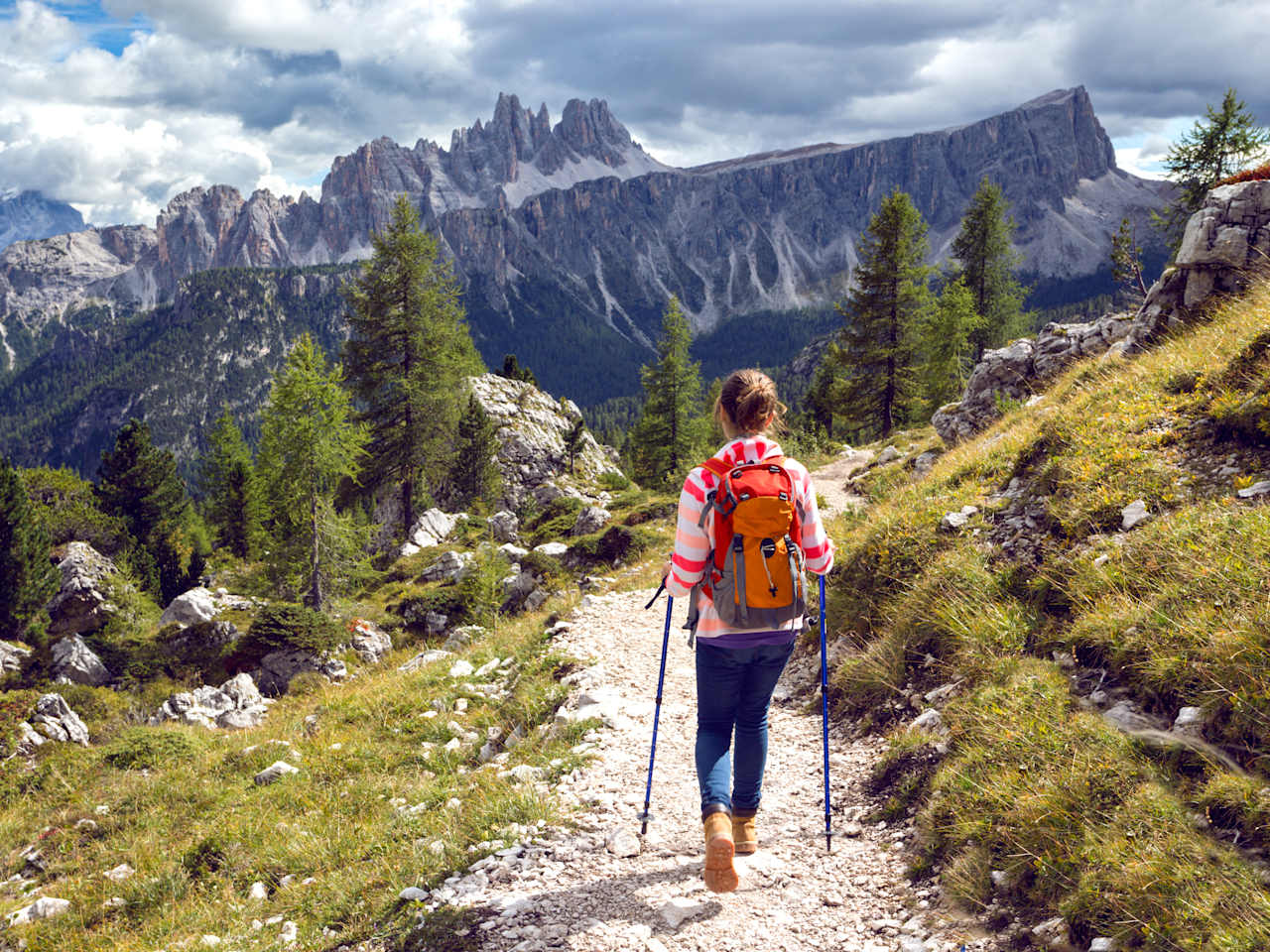 Eine Frau wandert auf einem schmalen Wanderweg vor einer spektakulären Bergkulisse in den Dolomiten in Südtirol, Italien ©shutterstock_1140667871