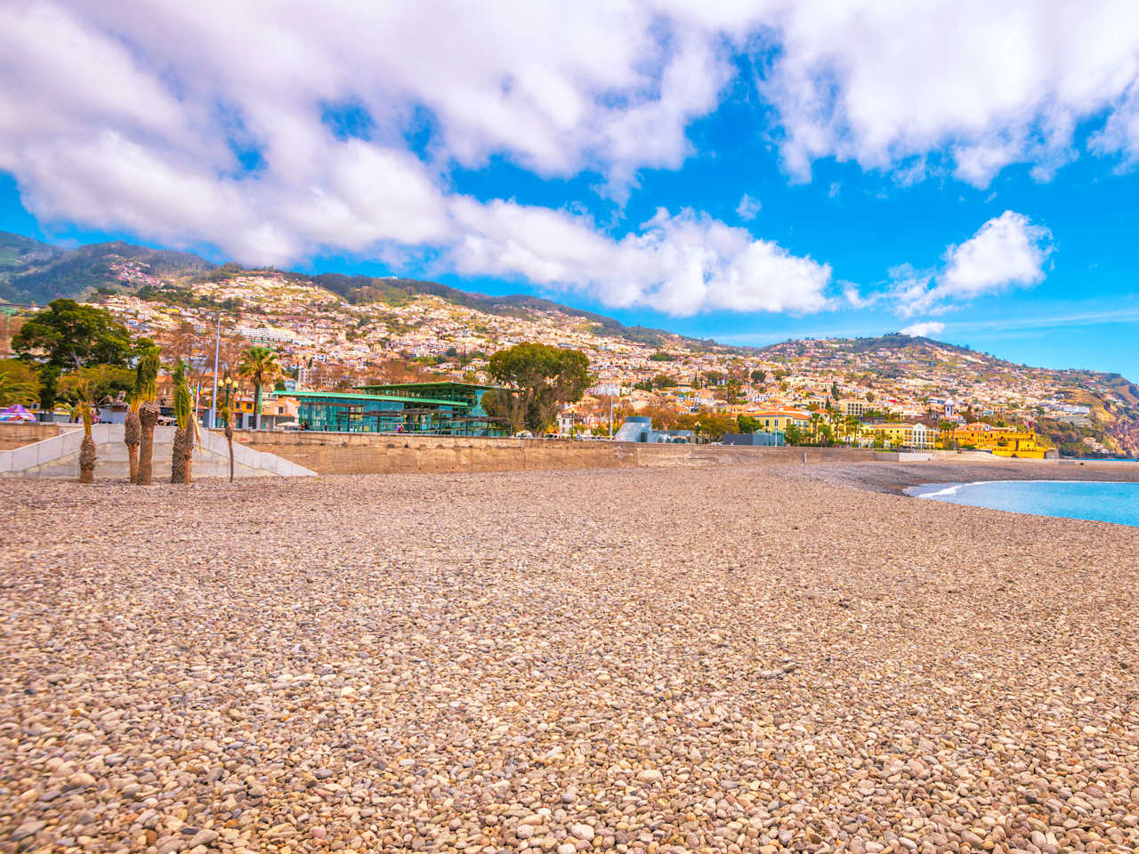 Ein Kiesstrand mit bergiger Landschaft im Hintergrund
