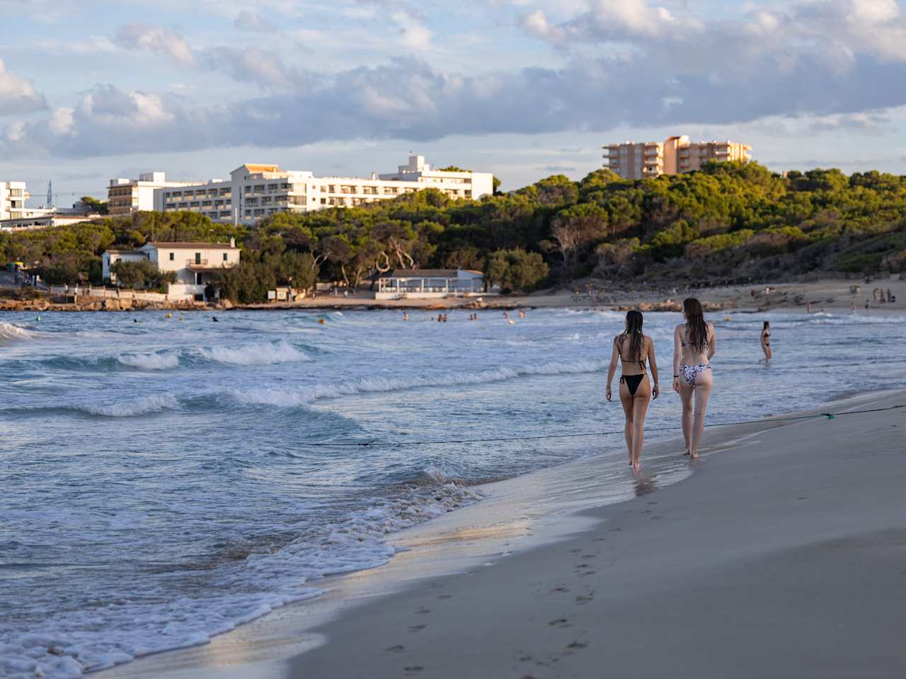 Zwei Frauen laufen am Strand Cala Agulla auf Mallorca, Spanien