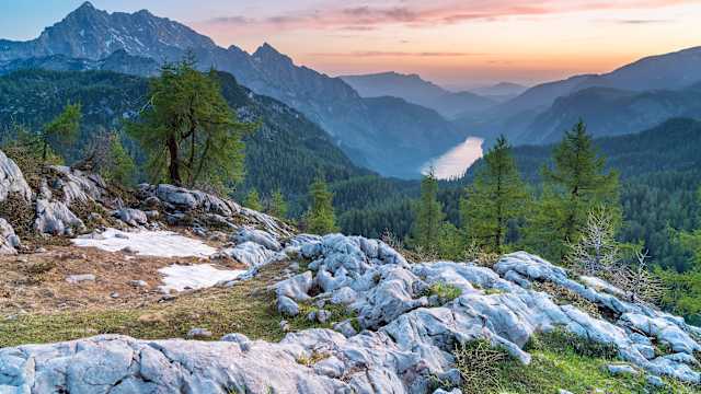 Blick auf ein Gebirge mit Bäumen bei Sonnenuntergang