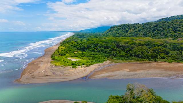 Ein faszinierendes Spiel von Blau- und Grüntönen, die sich in der Strandlandschaft zwischen Dschungel, Flussmündung und Meer in Dominical del Osa, Puntarenas, Costa Rica, mischen. © Kryssia Campos via Getty Images