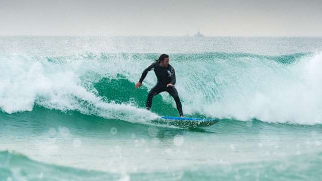 Ein Mann surft auf einer Welle.