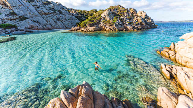 Eine Frau schwimmt am Cala Napoletana, Sardinien, Italien.