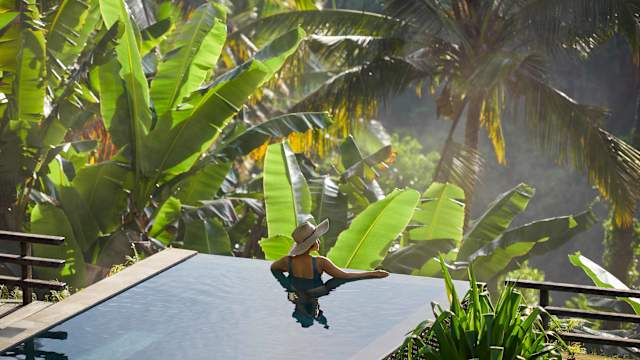 Eine Frau entspannt in einem Pool in Ubud auf Bali, Indonesien.