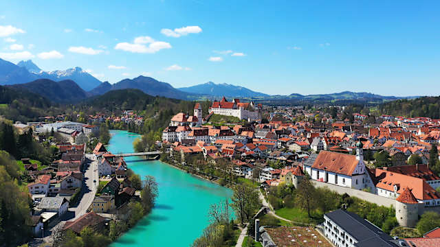 Blick über eine Stadt, durch die ein Fluss fließt. Im Hintergrund erheben sich Berge.