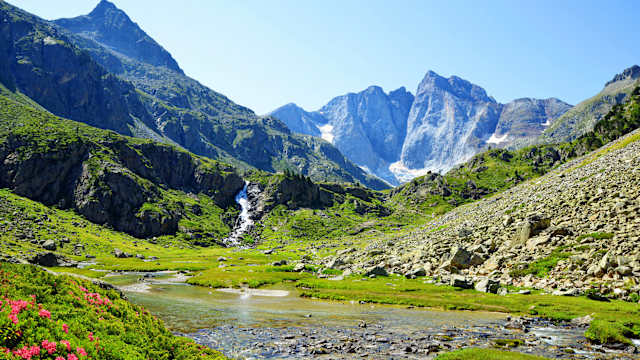 Ein kleiner Bach mit einem Wasserfall und einer Berglandschaft in den Pyrenäen.