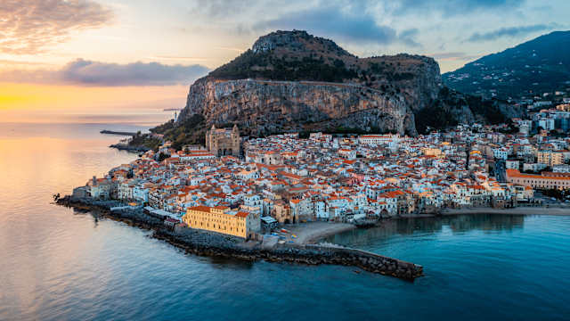 Stadtbild aus der Luft bei Sonnenaufgang, Cefalu, Sizilien. © Marco Bottigelli via Getty Images