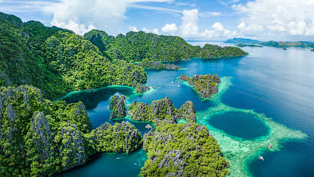 Dronenblick auf Lagune mit typisch philippinischen Balangay Booten.