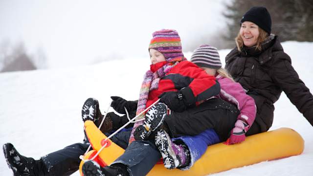 Familie rodelt in Bayern im Schnee. © sola deo gloria via Getty Images