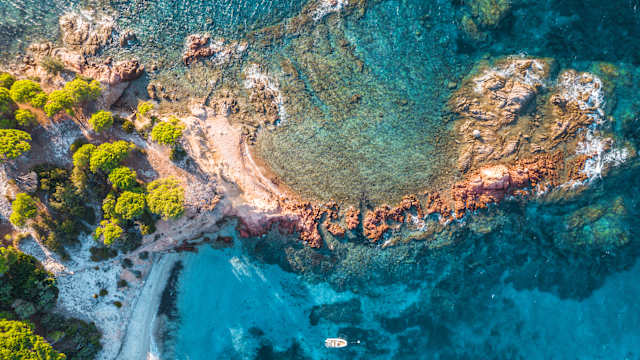 Luftbild von einem Strand mit Booten und Felsen.
