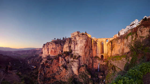 Puente Nuevo und die Stadt Ronda in der Abenddämmerung, Malaga, Spanien. © James O'Neil via Getty Images