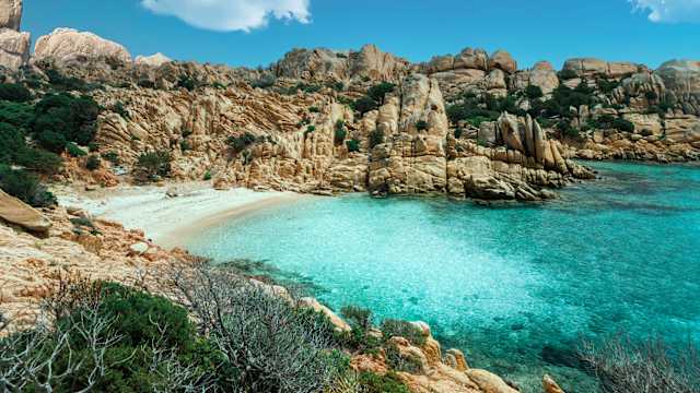 Blick auf eine versteckte Bucht mit kristallklarem Wasser, umrandet von Bergen. © wagnerm25 via Getty Images