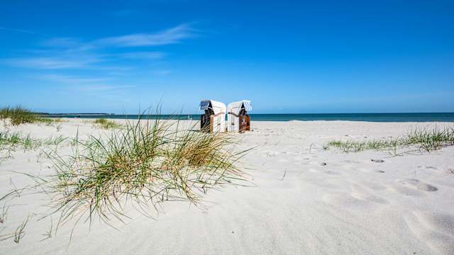 Zwei Strandkörbe stehen an einem leeren Strand.