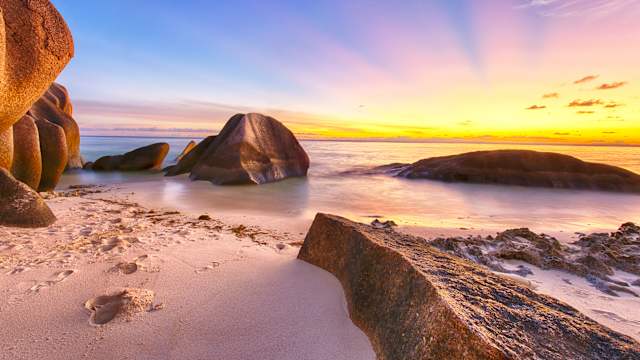 Sonnenuntergang am Strand mit hohen Felsen