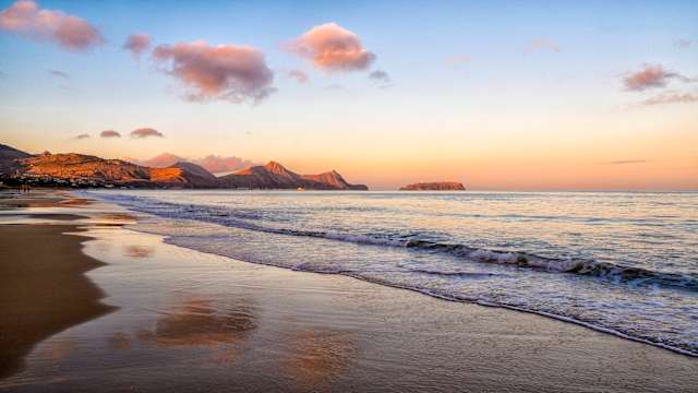 Ein leerer Strand bei Dämmerung mit Bergen im Hintergrund