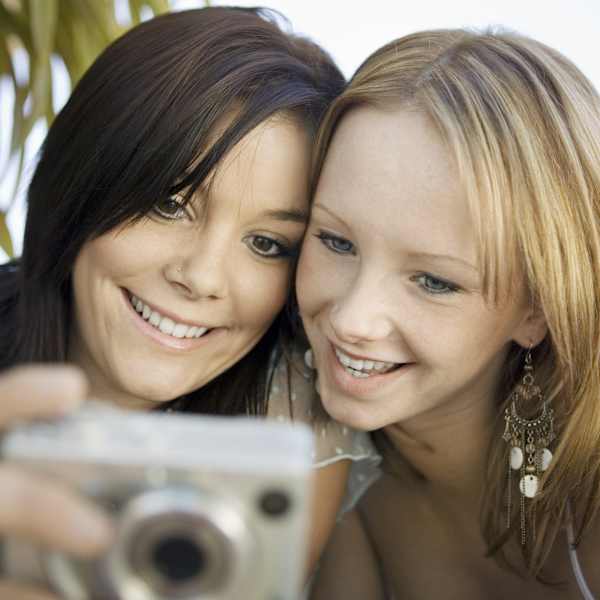 Zwei Frauen machen Urlaubsfoto mit Digitalkamera.