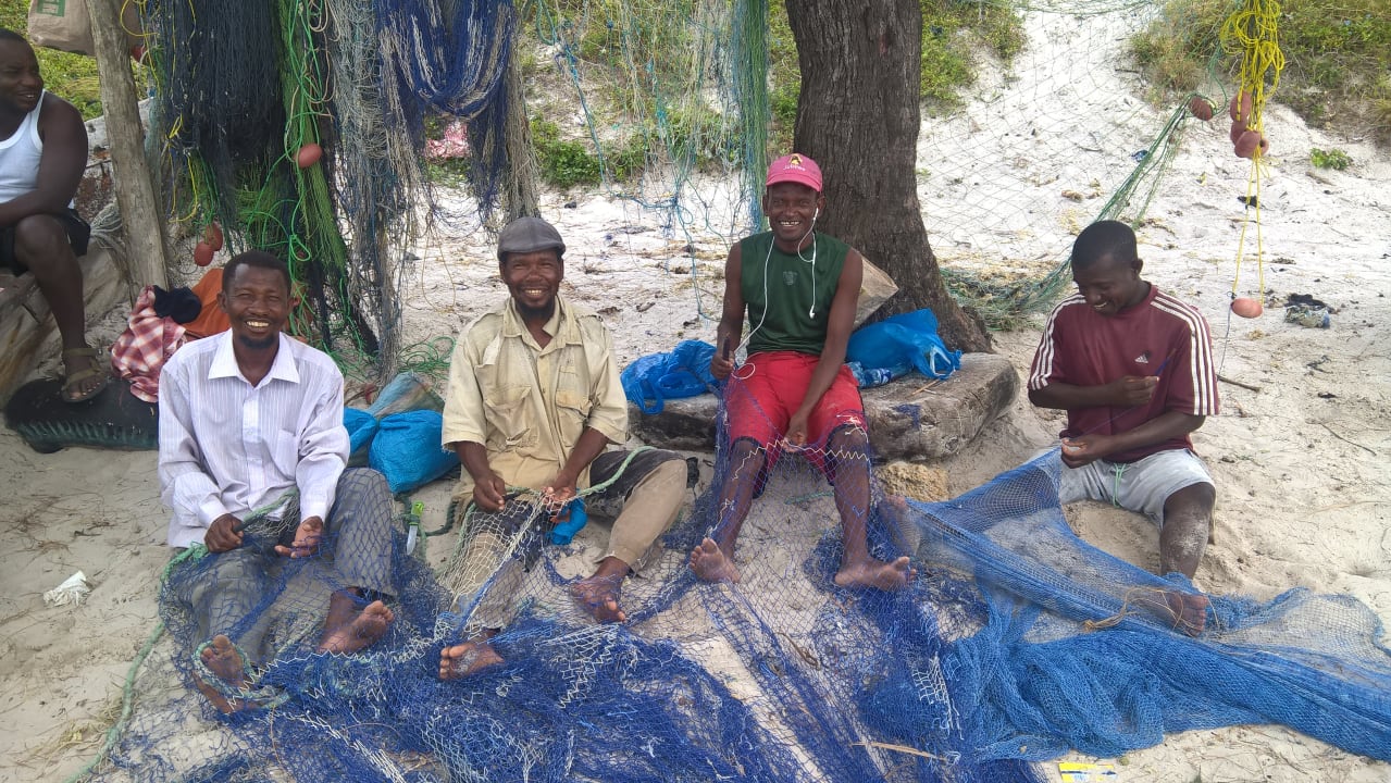 Fischer flicken Netze und freuen sich über ein Foto Bahari Beach Hotel