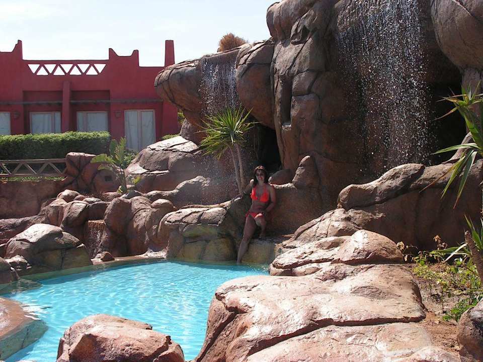 Pool mit Wasserfall und Bungalow dahinter Hotel Hauza Beach Resort