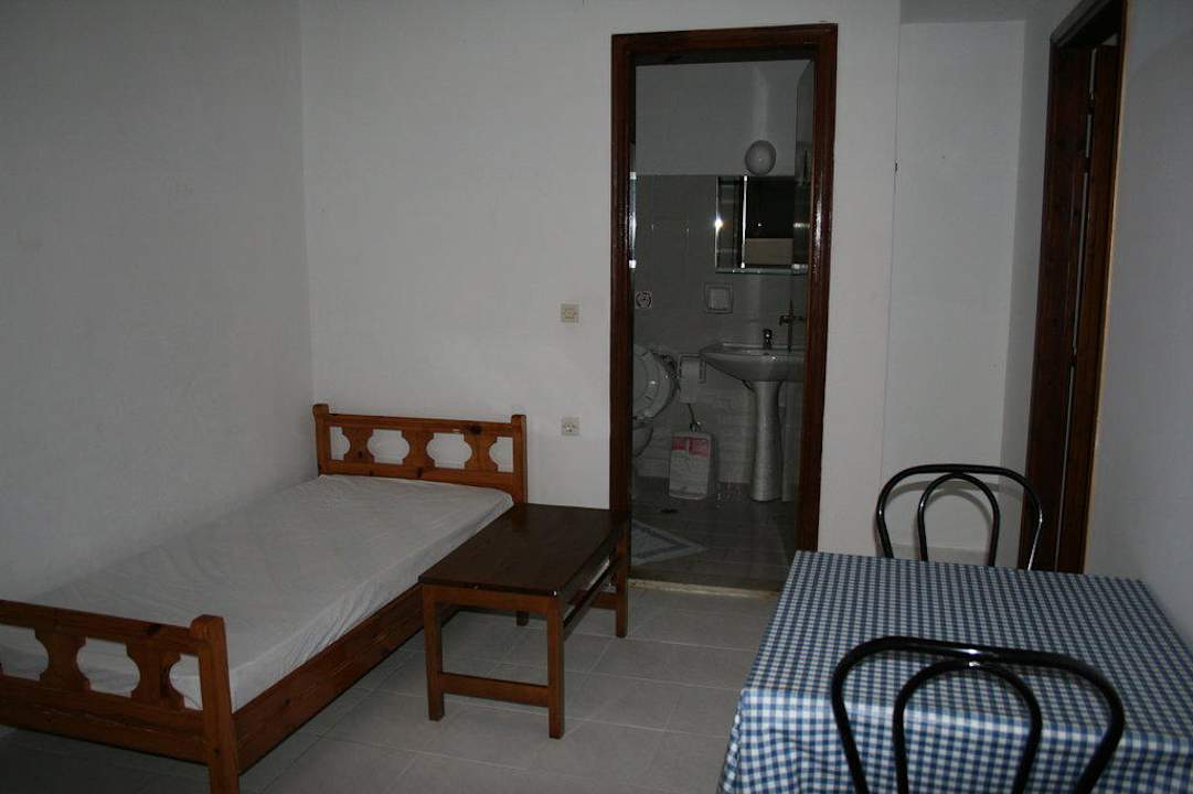 Gästebett mit Tisch / Badezimmereingang Hotel Karavos