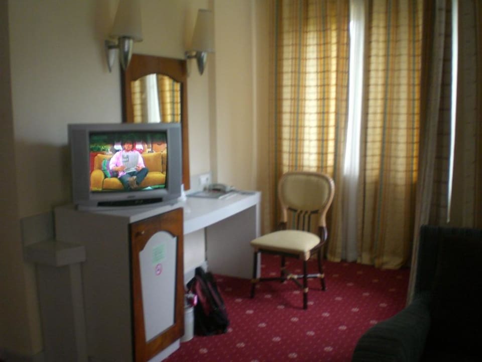 Fernseher auf Kühlschrank neben Tisch Le Jardin Resort