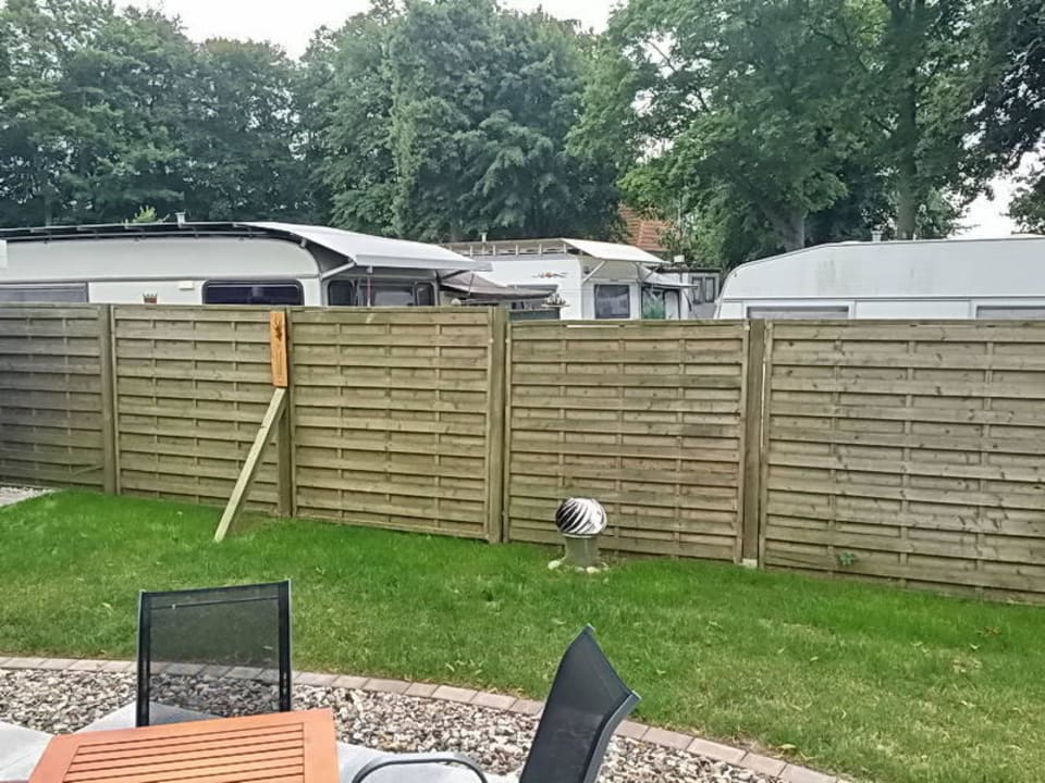 Blick vom Garten auf Zaun und Campingplatz Gutspark Rerik - Reetdachhaus Nr. 6