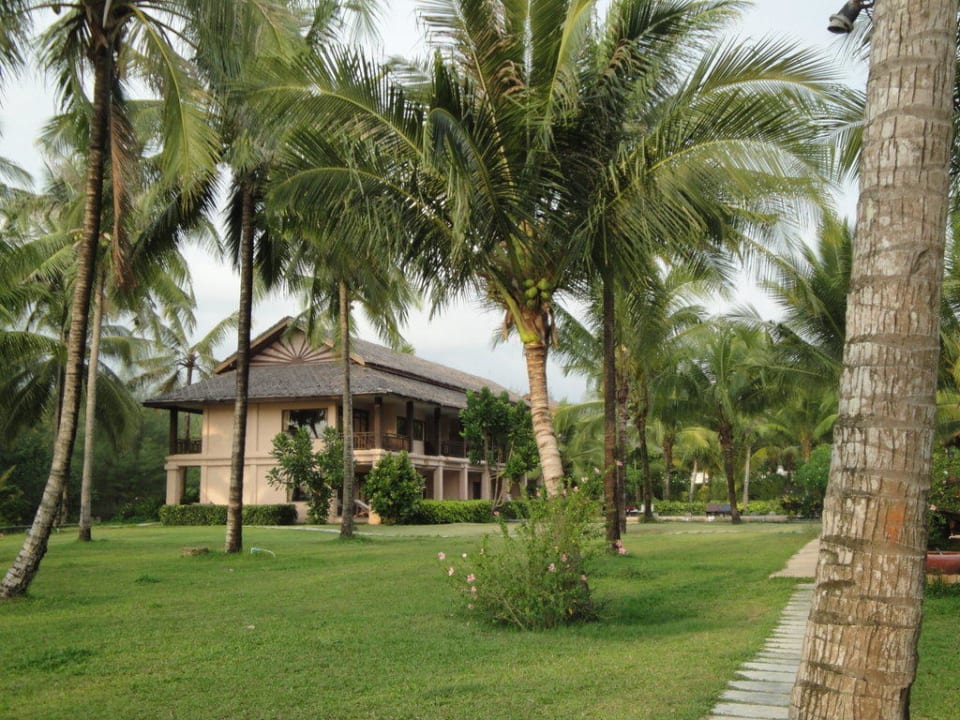 Blick vom tropischen Garten auf eines der Gebäude The Andamania Beach Resort & Spa