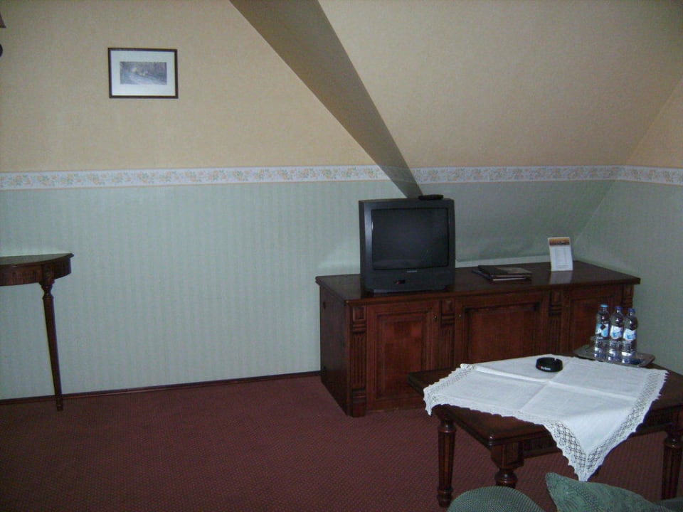 Wohnzimmer mit Tisch,Schrank mit Minibar und TV Hotel Amax
