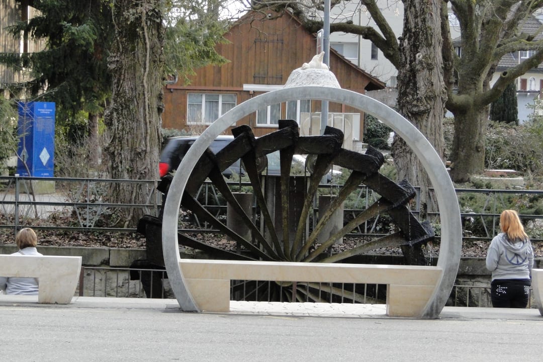 Water weehl and stone bench in front of the house Hotel Weisses Kreuz