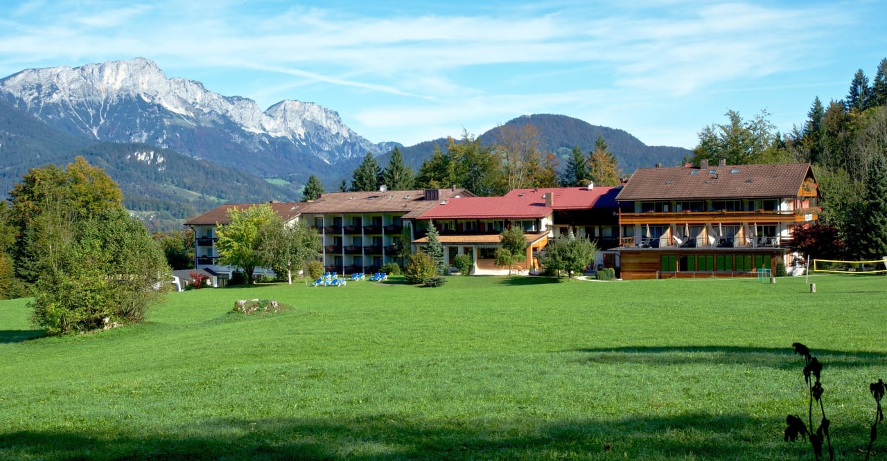 Blick über die weite Lichtung zum Hotelkomplex Alm- & Wellnesshotel Alpenhof