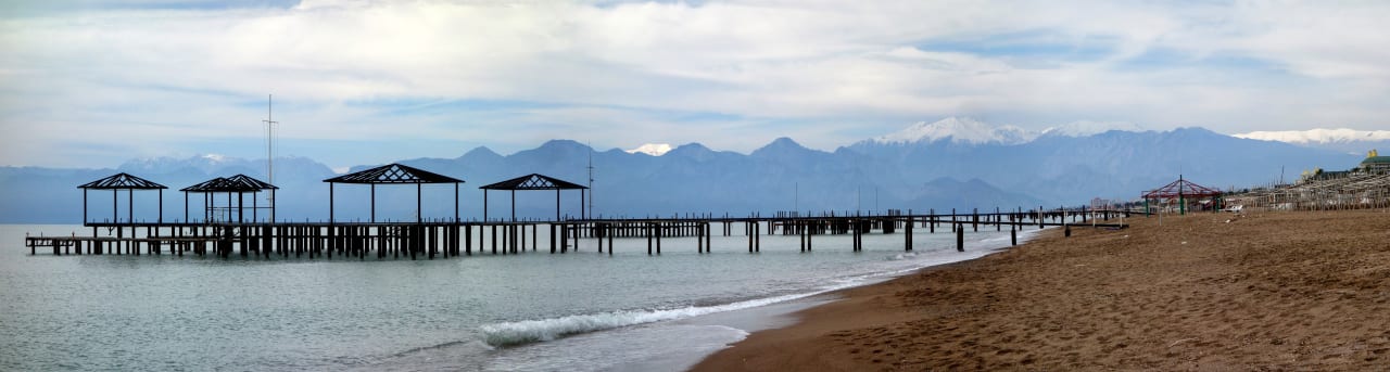 Blick vom Strand zu den hohen Bergen mit Schnee Royal Seginus