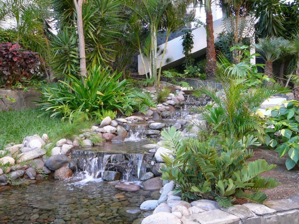 Hotelgarten mit kleinem Wasserfall allsun Hotel Lucana