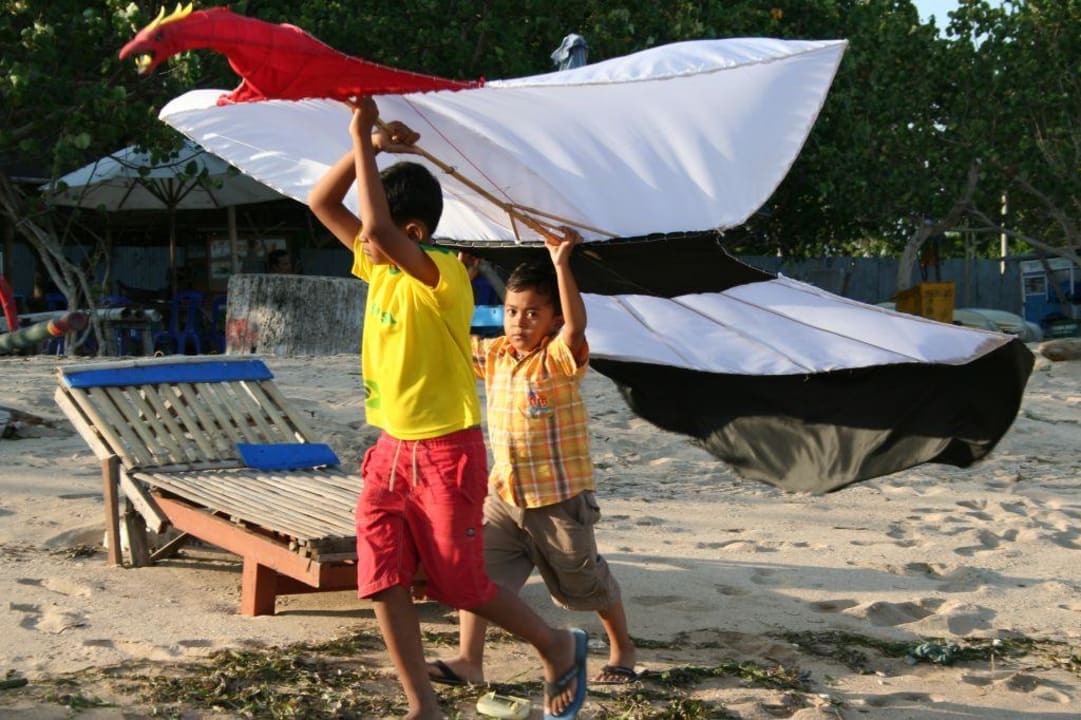 Kinder, die am Strand Drachen steigen lassen Puri Santrian