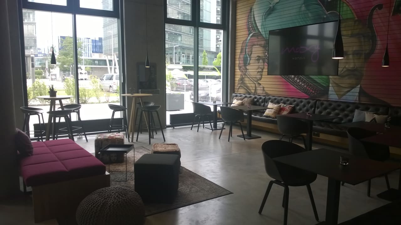 Sitzbereich in der Lobby mit großem TV MOXY Vienna Airport