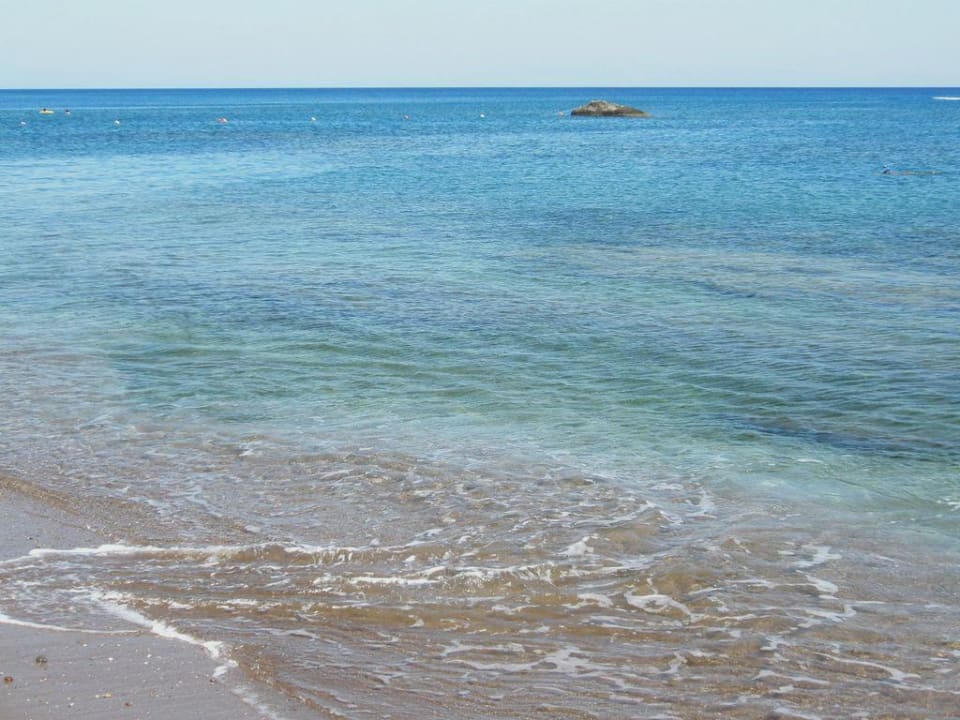 Sandstrand. Die dunklen Flecken sind Felsen Olympos Beach Hotel