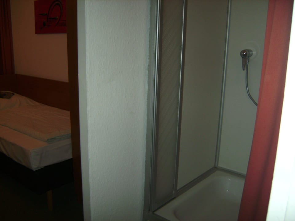 Dusche, im Hintergrund Bett Hotel John Brinckman
