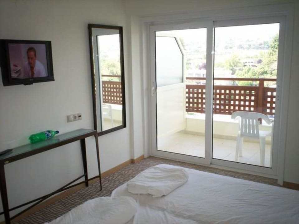 das Schlafzimmer mit TV, Spiegel und Balkon Olympian Bay Grand Resort